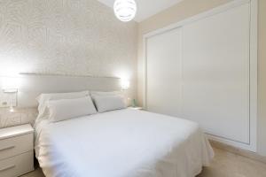 a bedroom with a white bed and a white wall at Lumbreras Host in Seville