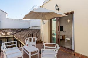 a patio with two white chairs and an umbrella at Lumbreras Host in Seville