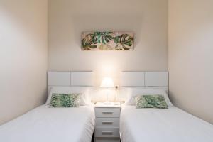Habitación con 2 camas individuales y paredes blancas. en Lumbreras Host, en Sevilla