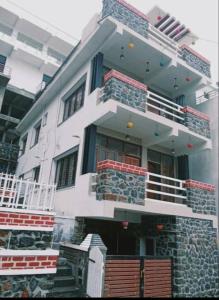 ein großes weißes Gebäude mit Balkon darüber in der Unterkunft Emmanuel Inn in Kodaikanal