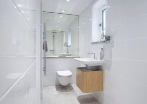 uma casa de banho branca com um WC e um lavatório em Little Barn at Coppice Barn, Birdham em Birdham