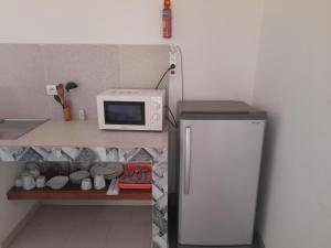 a small kitchen with a microwave and a refrigerator at Appart Ziguinchor in Ziguinchor