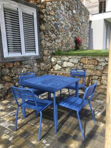 una mesa y sillas azules con una pared de piedra en Belvedere20guesthouse, en Finale Ligure