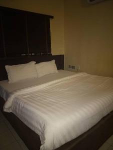 a large white bed with white sheets and pillows at Winstons Place Hotel in Onitsha