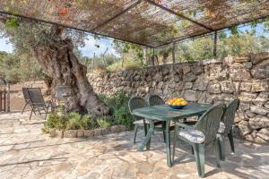 een patio met een tafel en stoelen en een stenen muur bij Deià semi-detached sunny country house, near GR221 in Deia