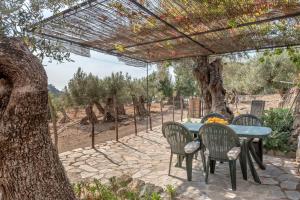 een patio met een tafel en stoelen onder een pergola bij Deià semi-detached sunny country house, near GR221 in Deia