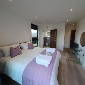 a bedroom with a large bed with towels on it at Central Penthouse with Hot Tub & Views 24 Cheltenham in Cheltenham +14 photos