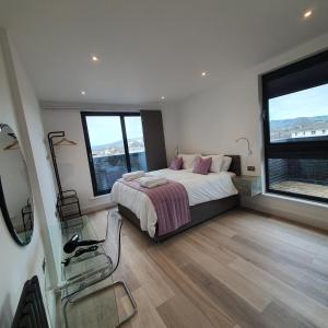 a bedroom with a bed and two large windows at Central Penthouse with Hot Tub & Views 24 in Cheltenham