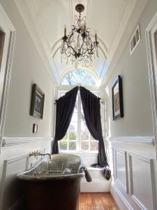 a bathroom with a chandelier and a tub in front of a window at The Twelve Oaks Bed & Breakfast in Covington