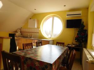eine Küche und ein Esszimmer mit einem Tisch und einem Fenster in der Unterkunft Csetáj Vendégház in Hajós