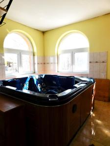 eine große Badewanne in einem Zimmer mit 2 Fenstern in der Unterkunft Csetáj Vendégház in Hajós