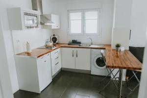 a kitchen with white cabinets and a washer and dryer at Apartamentos ZHR 2 in Zahara de los Atunes