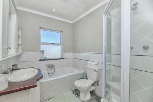 a white bathroom with a toilet and a sink at Colours of the Sea - Main house in Struisbaai +13 photos