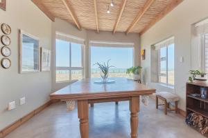 a dining room with a table and some windows at Colours of the Sea - Main house in Struisbaai