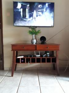 uma mesa de madeira com uma televisão na parede em Casa das Flores em Chapada dos Guimarães