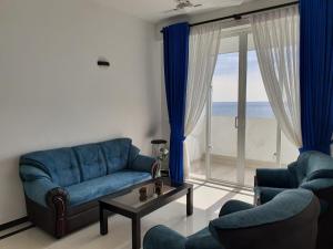 een woonkamer met een blauwe bank en stoelen en een raam bij New 2 bedroom apartment, 100m away from the beach in Dehiwala