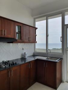 een keuken met houten kasten en een groot raam bij New 2 bedroom apartment, 100m away from the beach in Dehiwala