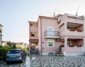 un edificio rosa con un'auto parcheggiata di fronte di Apartments Zaharija a Rovigno (Rovinj)