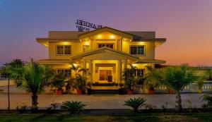 una casa amarilla con palmeras delante en Playotel Resort Bhopal, en Bhopal