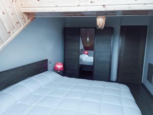 1 dormitorio con 1 cama blanca grande y espejo en Apartamento, Ático, Casa, PLAYA LAS CATEDRALES, en San Cosme de Barreiros
