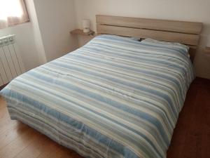 a bed with a blue and white striped blanket at Appartamento Prima Rosa in Primaluna