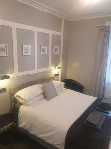 - une chambre avec un lit doté de draps et d'oreillers blancs dans l'établissement The Coastal Inn Outbuilding, à Cellardyke