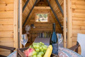 a wooden table with a bottle of wine and grapes at Aphrodite Family Eco Camping in Neo Chorio