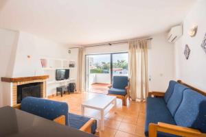 a living room with blue chairs and a fireplace at Oura Parque Apartamentos Turisticos in Albufeira