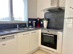 a kitchen with white cabinets and a sink and a stove at REF 052 Maison pour 7 personnes à proximité du Golfe du Morbihan à louer pour les vacances in Arzon