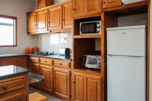 a kitchen with wooden cabinets and a white refrigerator at Pretty house close to metro and wine cellars - host 8 in Vila Nova de Gaia