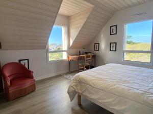 a bedroom with a bed and a chair and windows at REF 052 Maison pour 7 personnes à proximité du Golfe du Morbihan à louer pour les vacances in Arzon +12 photos