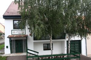a white house with a green door and trees at Csillagtúra Panzió in Eger