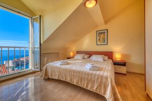 ein Schlafzimmer mit einem Bett und einem großen Fenster in der Unterkunft Portolan's Amazing Sea & Old Town View in Dubrovnik