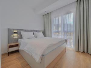 a white bedroom with a large bed and a window at Horizon Two bedroom Apartment with sea view Jake in Becici +12 photos