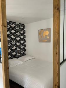 a bedroom with a white bed with a black and white headboard at le logis du port in Meschers-sur-Gironde