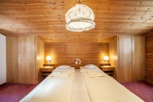 un grande letto in una camera in legno con lampadario a braccio di Residence Pichler Apartment 5 a San Leonardo in Passiria
