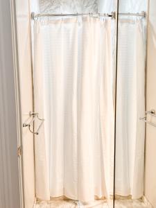 La salle de bains est pourvue d'une douche avec un rideau de douche blanc. dans l'établissement Bon Maison Guest House, à La Nouvelle-Orléans