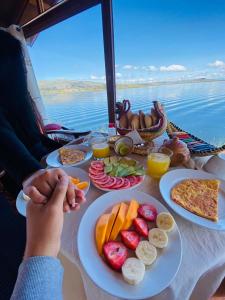 een tafel met borden met voedsel erop met uitzicht op het water bij Luz del Titicaca Lodge in Puno