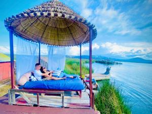 un hombre y un niño acostados en una cama bajo un paraguas en Luz del Titicaca Lodge, en Puno