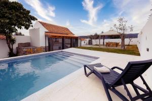 una piscina con una silla y una casa en Pomar das Oliveiras - Moradia com Piscina privada e carregamento VE gratuito, en Carvalhal Cimeiro