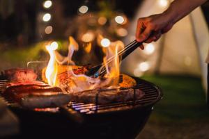 a person is cooking food on a grill at Cocoon Village - Glamping - Domaine des Grottes de Han in Rochefort