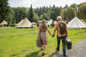 a man and woman walking down a path holding hands at Cocoon Village - Glamping - Domaine des Grottes de Han in Rochefort