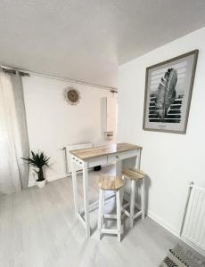 a white kitchen with a table and two stools at Le Golf Balnéo - Cosy & SPA in Saint-Étienne