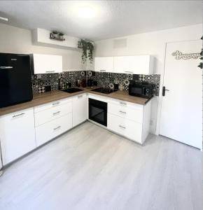 a kitchen with white cabinets and a black appliance at Le Golf Balnéo - Cosy & SPA in Saint-Étienne