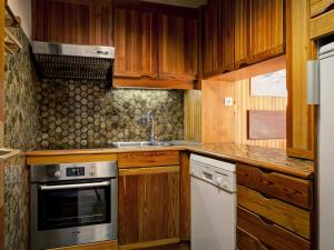a kitchen with wooden cabinets and a sink and a stove at Appartement Courchevel 1850, 3 pièces, 6 personnes - FR-1-514-27 in Courchevel