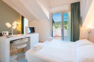 a hotel room with a bed and a desk and a window at Hotel Melograno in Spotorno