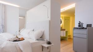a bedroom with a white bed with a mirror at Neuro Campus Hotel in Vitznau