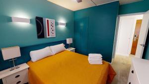 a bedroom with a yellow bed and blue walls at Apartamentos Eldorado in Lloret de Mar