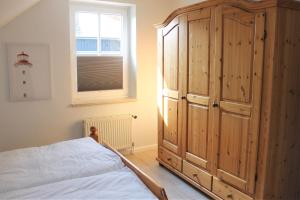 sypialnia z dużą drewnianą szafką obok łóżka w obiekcie "Pappelhof - Whg 4" w mieście Grömitz