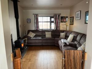 a living room with a leather couch and a stove at Strand Awaits Holiday Home in Cork